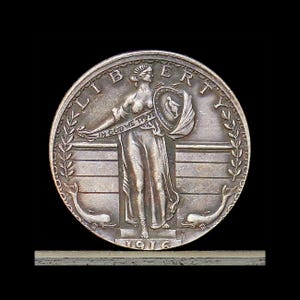 May include: A silver-toned Standing Liberty quarter coin dated 1916. The obverse features a central figure holding a shield and a banner inscribed with IN GOD WE TRUST. The word LIBERTY is arched across the top, with two dolphins at the base.