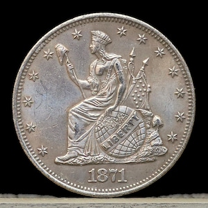 May include: Silver coin with a portrait of Liberty seated on a globe, holding a staff and a cap. The coin has 13 stars around the edge and the year 1871 inscribed below.