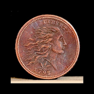 May include: A copper coin with the word "LIBERTY" arched across the top. The coin features a profile of a woman with flowing hair and the date "1793" at the bottom. The coin has a detailed, aged appearance.