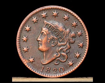 May include: A copper coin with a profile of a woman wearing a head covering and the word "LIBERTY". The coin is dated 1820 and surrounded by stars. The coin has a dark brown patina.