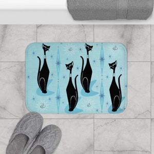 May include: A blue bath mat with a repeating pattern of black cats and white stars. The cats are in a sitting position with their tails curled around their bodies.