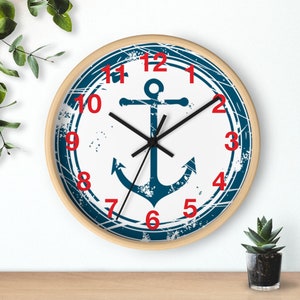 May include: A white and blue nautical clock with a distressed look. The clock face features a blue anchor with a black outline and red numbers. The clock has a wooden frame.