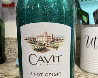 Puede incluir: Una botella de vino verde con purpurina con una etiqueta blanca que dice "CAVIT COLLECTION PINOT GRIGIO 2020 DELLE VENEZIE DENOMINAZIONE ORIGINE CONTROLLATA EXCELLENCE IN ITALIAN CRAFTSMANSHIP IMPORTED FROM ITALY"