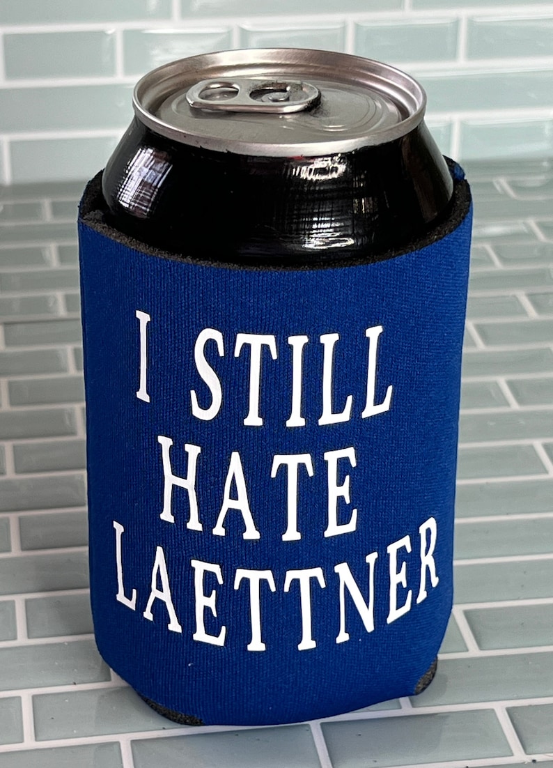 Puede incluir: Un enfriador de latas azul con el texto "I still hate Laettner" en blanco.