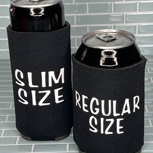 Puede incluir: Dos enfriadores de latas de neopreno negro. El enfriador de la izquierda tiene el texto "SLIM SIZE" impreso en blanco. El enfriador de la derecha tiene el texto "REGULAR SIZE" impreso en blanco.