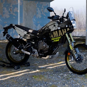 May include: A black and white Yamaha Ténéré 700 motorcycle with gold accents. The motorcycle has a windshield, a black exhaust, and the Yamaha logo is visible. The bike is parked on a gravel surface.