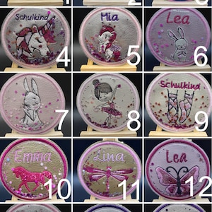 Könnte beinhalten: Ein Set mit 16 runden, personalisierten Patches mit verschiedenen Designs und Namen. Die Patches sind aus einem weichen, strukturierten Stoff mit Glitzerakzenten gefertigt. Die Designs beinhalten ein Einhorn, eine Ballerina, einen Schmetterling, eine Libelle, einen Flamingo, eine Eule, ein Kaninchen und einen Sternschnuppen. Die Patches sind perfekt, um Rucksäcken, Jacken oder anderen Gegenständen eine persönliche Note zu verleihen.