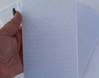 May include: Three sheets of white adhesive-backed paper with a grid of small, round, white circles.