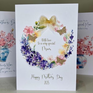 Tarjeta de lujo para el Día de la Madre hecha a mano para mamá. Hermosas flores silvestres decoradas con mariposas con purpurina en 3D, flores violetas, gemas y cinta.