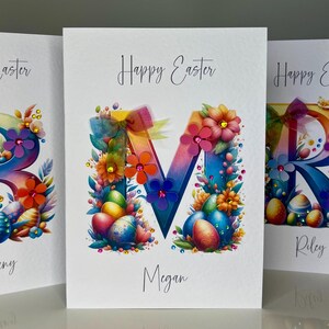 Gepersonaliseerde paaskaart. Kaart met initialen, M. Handgemaakte paaskaart met kleurrijke 3D-bloemen, regenbooglint en veel edelstenen. Luxe naamkaartje
