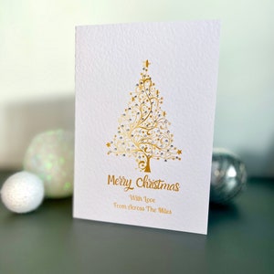 Una tarjeta navideña sencilla con gemas brillantes, tarjeta navideña dorada con un árbol de Navidad para seres queridos que están lejos, tarjeta navideña decorada a mano, tarjeta navideña dorada.