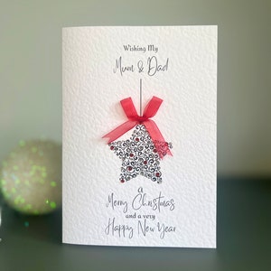 Un biglietto di auguri di NATALE contemporaneo per mamma e papà, una pallina di Natale a forma di stella decorata con gemme rosse e argentate, biglietto di auguri di Natale per mamma e papà