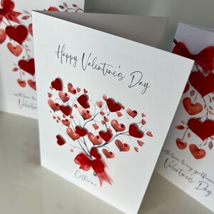 May include: A white card with a red heart-shaped bouquet of hearts and the text "Happy Valentine's Day" and the name "Catherine" at the bottom.