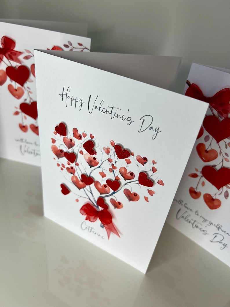 May include: A white card with a red heart-shaped bouquet of hearts and the text "Happy Valentine's Day" and the name "Catherine" at the bottom.