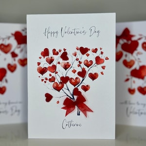 May include: A white card with a red heart-shaped tree with red hearts on the branches. The card says "Happy Valentine's Day" and "Catherine".