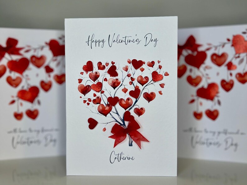 May include: A white card with a red heart-shaped tree with red hearts on the branches. The card says "Happy Valentine's Day" and "Catherine".