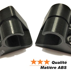 Puede incluir: Dos clips de plástico negro impresos en 3D con un diseño de bisagra. Los clips están diseñados para sujetar objetos en su lugar. El texto "PRINT3D63" es visible en la parte inferior de los clips. El texto "Qualité Matière ABS" es visible en la parte inferior de la imagen.