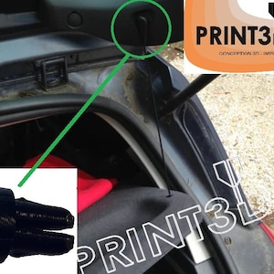 May include: A black plastic car boot latch release handle with a textured surface. The handle is attached to a black string. The string is attached to a black plastic hook. The hook is attached to the inside of a car boot. The text "PRINT3D63" is visible in the background.