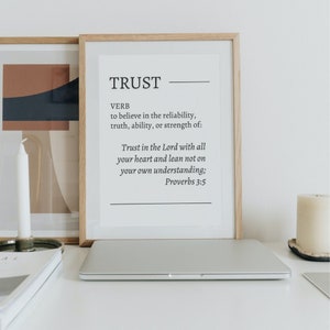 Puede incluir: Una impresión enmarcada con fondo blanco y texto negro. El texto dice "TRUST" y define la palabra como un verbo. La impresión también incluye una cita de Proverbios 3:5, "Confía en el Señor con todo tu corazón y no te apoyes en tu propia inteligencia."