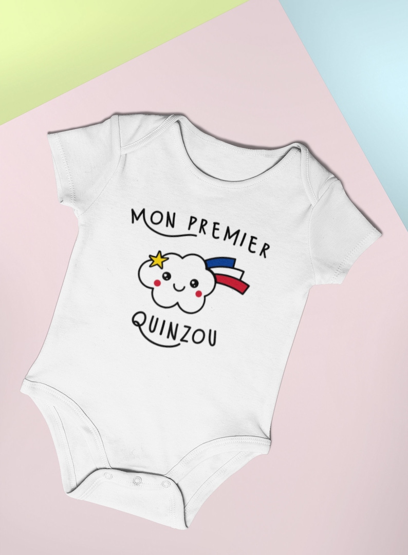 May include: White baby onesie with a cute cartoon cloud with a star and rainbow. The text "MON PREMIER QUINZOU" is printed on the onesie.
