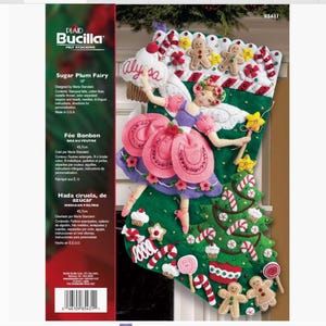 Könnte beinhalten: Ein Filz-Strumpf-Set mit einem Sugar Plum Fairy-Design. Der grüne Strumpf ist mit einer Fee in einem rosa Kleid, Lebkuchenmännern, Zuckerstangen und einem Weihnachtsbaum verziert. Das Set enthält Anleitungen und Materialien.
