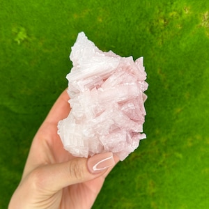 Puede incluir: Un cúmulo de cristales de sal rosa del Himalaya con una textura rugosa y natural. Los cristales son translúcidos y tienen un delicado tono rosado.