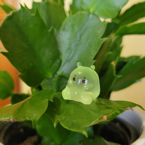 Cute luminous green glow in the dark Slime Ball plant safe magnet. Sits on leafy plant secured by plant safe magnet, plant critter accessory