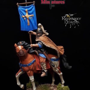 May include: A hand-painted miniature of a medieval knight on horseback, holding a blue banner with a gold cross. The knight is wearing a brown cloak and chainmail armor. The horse is brown with white markings. The miniature is unpainted and is part of a collection of historical figures.