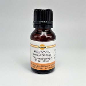 May include: A small brown glass bottle with a black cap, labeled "GROUNDING Essential Oil Blend" with the text "*For external use only* 15 ml ~ 0.5 oz" and the company name "The Soap Opera".
