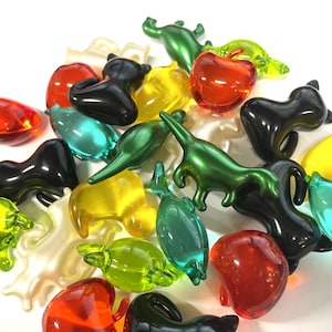 Könnte beinhalten: Eine Sammlung bunter, durchsichtiger Plastikfiguren in verschiedenen Formen, darunter Tiere, ein Apfel und ein Fisch. Die Figuren sind aus klarem Plastik mit verschiedenen Farben, darunter Rot, Grün, Gelb, Blau und Schwarz.