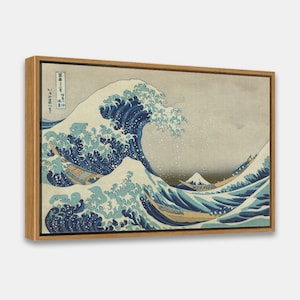 May include: A framed print of a Japanese woodblock print depicting a large wave crashing over three boats. The wave is blue and white, and the boats are small and brown. The background is a light gray with a mountain in the distance. The print is titled "The Great Wave off Kanagawa" in Japanese characters.