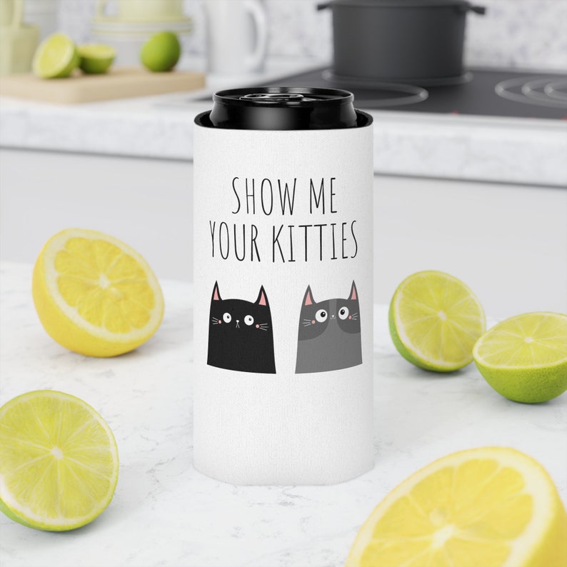May include: White can cooler with black text that says "Show me your kitties". Two black and gray cartoon cats with pink noses are on the cooler.