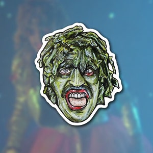 May include: A hand-drawn illustration of a green-skinned creature with a large mouth and sharp teeth. The creature is covered in seaweed and has a menacing expression.