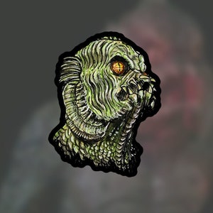 May include: A close-up of a green, scaly creature with a large, toothy mouth and one visible yellow eye. The creature is drawn in a detailed, realistic style.