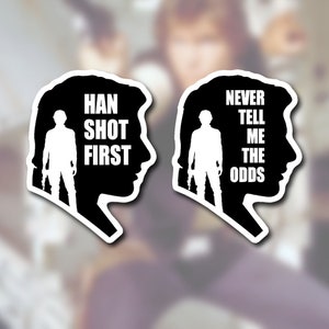 May include: Two black and white silhouette stickers of Star Wars characters. The first sticker features Han Solo with the text "Han Shot First". The second sticker features Luke Skywalker with the text "Never Tell Me The Odds".