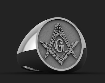 May include: A silver ring featuring an intricate engraving of a compass and square, a traditional symbol of Freemasonry. The ring has a 'G' at the centre of the design.