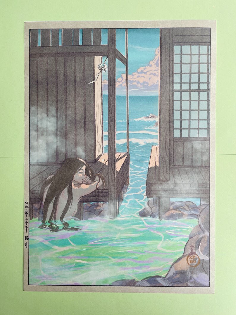May include: A woodblock print showing a woman bathing in a natural hot spring. The woman is seated in the water, which is a vibrant green colour. The water is surrounded by rocks and a wooden structure. The background shows a view of the ocean and sky.