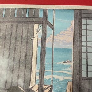 May include: A woodblock print depicting a view of the ocean from a Japanese home. The print features a wooden window frame with a view of the ocean and sky. The ocean is a light blue colour with white waves. The sky is a light blue colour with white clouds. The print is framed in a wooden frame.
