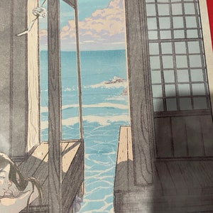 May include: A wooden-framed window with a view of the sea. The water is a light blue colour and there are white clouds in the sky. The window is open and the sea is visible through the opening.