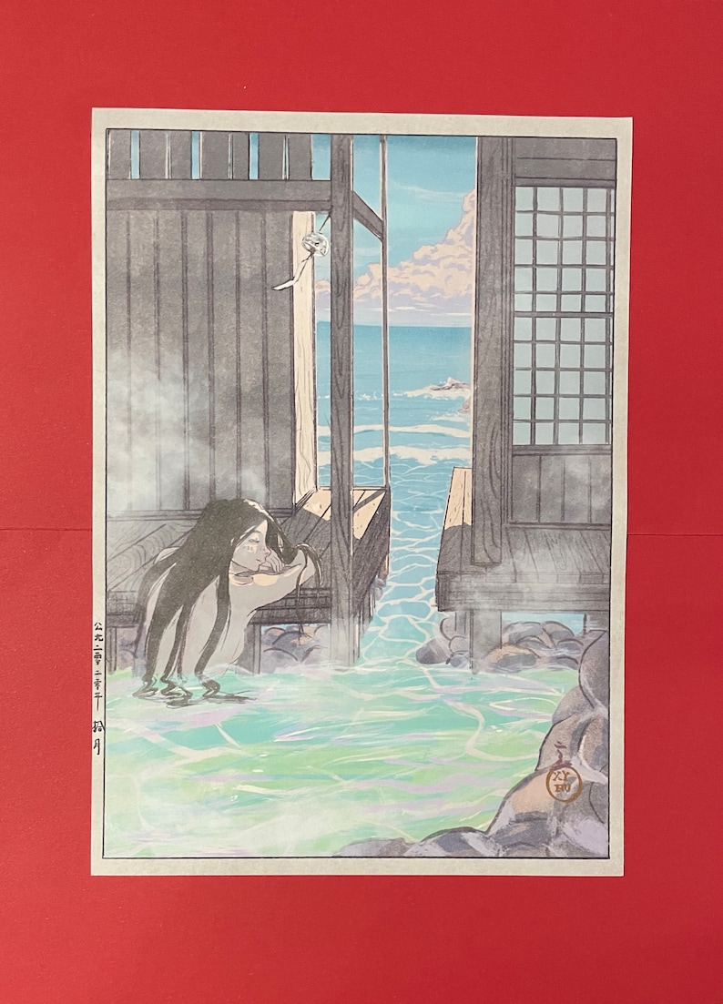 May include: A Japanese woodblock print showing a woman taking a bath outdoors, with a view of the sea. The bath is surrounded by rocks and steam. The woman has long black hair and is wearing a white cloth. The print is in shades of blue, green, and brown.