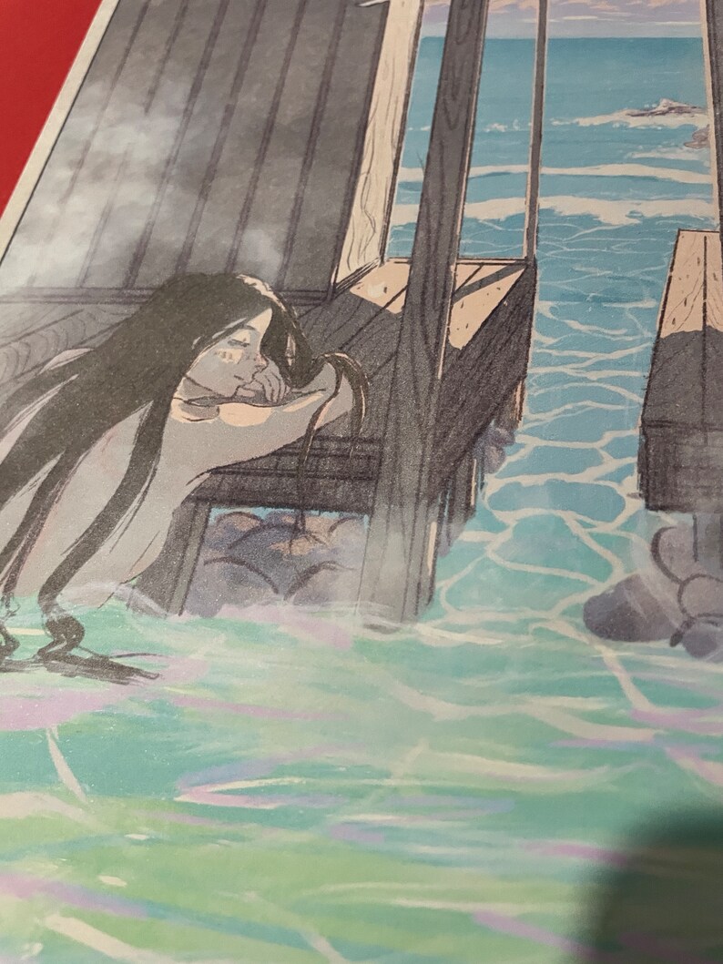May include: A woman with long dark hair leans against a wooden railing, looking out at the ocean. The water is a light blue and green, with whitecaps. The woman's face is obscured by her hair, but she appears to be wearing a white dress.