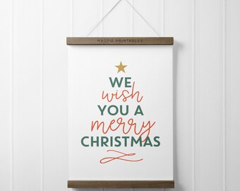May include: A white Christmas-themed poster with the text "We wish you a merry Christmas" in red and green, topped with a gold star. The poster is held by a wooden frame and hung with a white string.