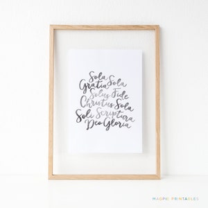 以下が含まれることがあります： グレーのグラデーションで「Sola Gratia Sola Solus Fide Christus Sola Soli Scriptura Deo Gloria」というテキストが書かれた額装されたプリントです。