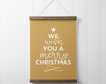 May include: A mustard yellow printable poster with the text "We wish you a merry Christmas" in white text. The text is arranged in a Christmas tree shape with a white star at the top.