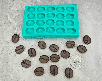 May include: A teal silicone mold with 24 individual cavities shaped like coffee beans. There are 14 brown coffee bean-shaped candies scattered around the mold. The text "Vanilla Cotton Aromas" is printed on the mold.