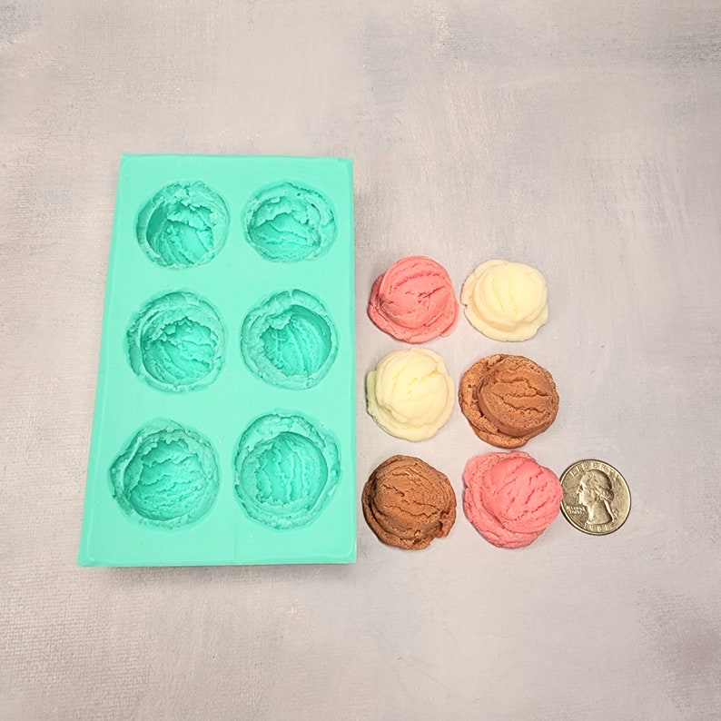 K&ouml;nnte beinhalten: Eine t&uuml;rkisfarbene Silikon-Eiscremeform mit sechs Vertiefungen, neben sechs Miniatur-Eiswaffeln in verschiedenen Geschmacksrichtungen: Vanille, Schokolade und Erdbeere.