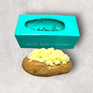 May include: A turquoise silicone mould for making baked potato shapes. The mould has the text "Vanilla Cotton Aromas" on the bottom. A baked potato with mashed potatoes on top is shown below the mould.