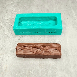 Puede incluir: Un molde de silicona turquesa con el texto "Vanilla Cotton Aromas" y una barra de chocolate.