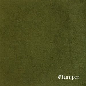 May include: Close-up of a textured fabric in a deep olive green color. The fabric has a soft, velvety appearance. The text "#Juniper" is in the bottom right corner.