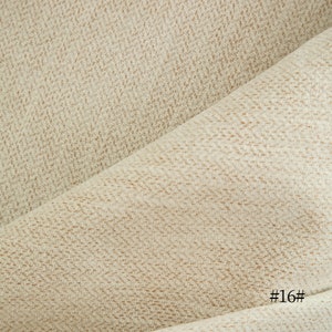 May include: Close-up of a beige fabric with a subtle textured pattern. The fabric is folded in half, creating a diagonal line. The text "#16#" is visible in the bottom right corner.